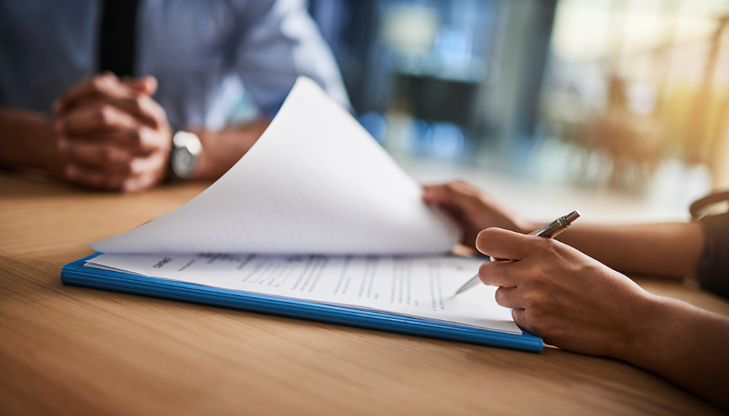 Cropped photo of two people reviewing paperwork at a desk