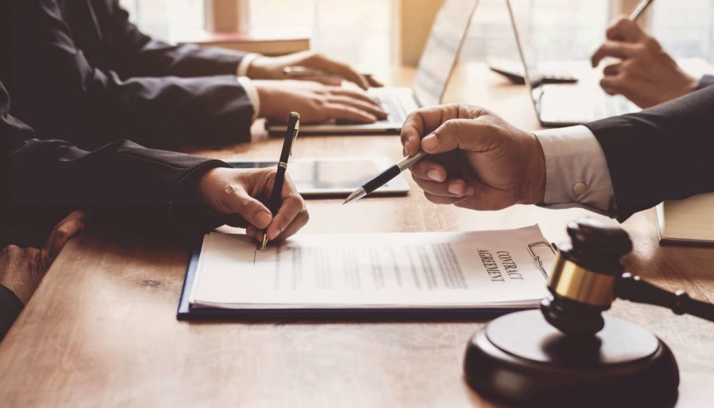 people signing legal contract with gavel