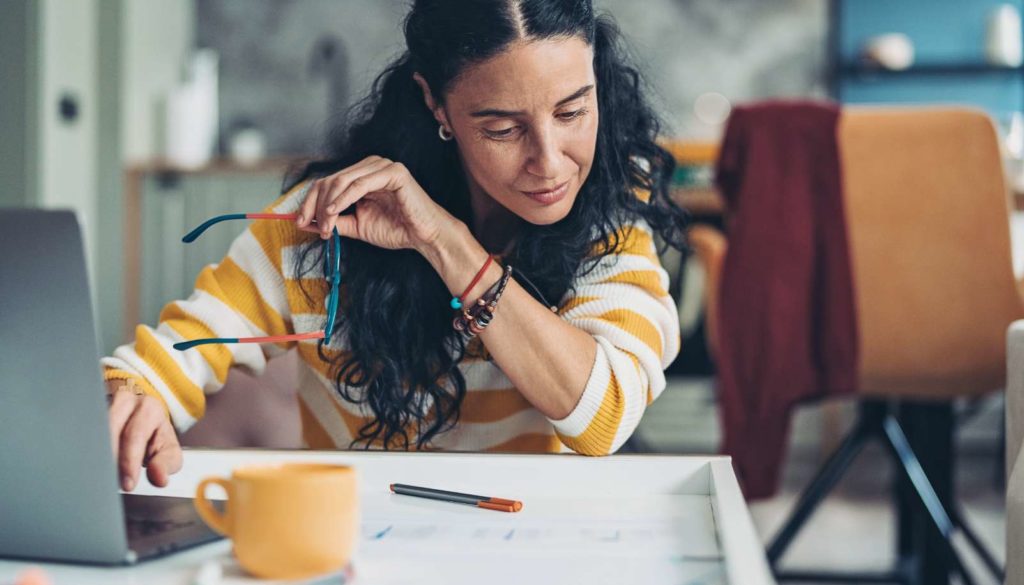 woman looking a paper while on laptop