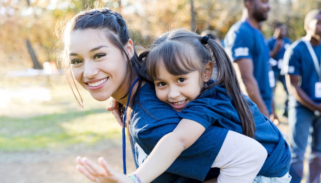 Volunteer woman holding child on back